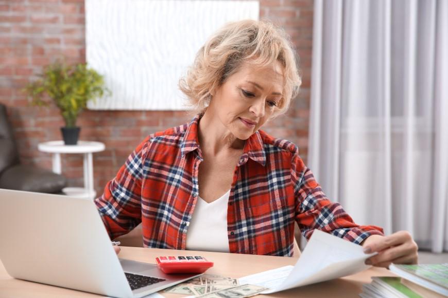 Woman looking at papers and working at laptop