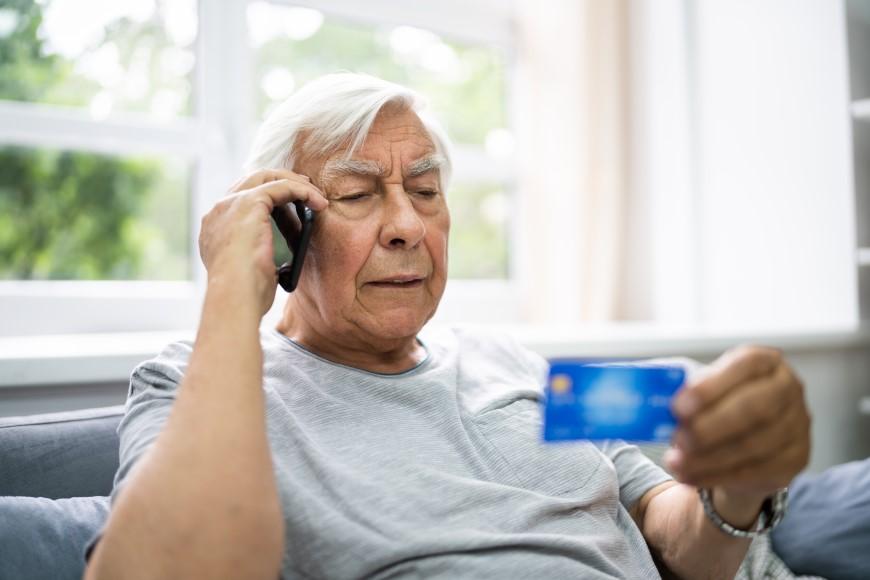 Older man on cell phone holding credit card
