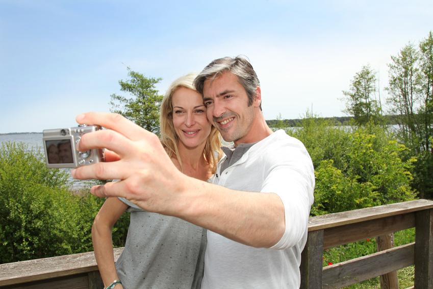 Couple posnig for a selfie next to a wooden fence