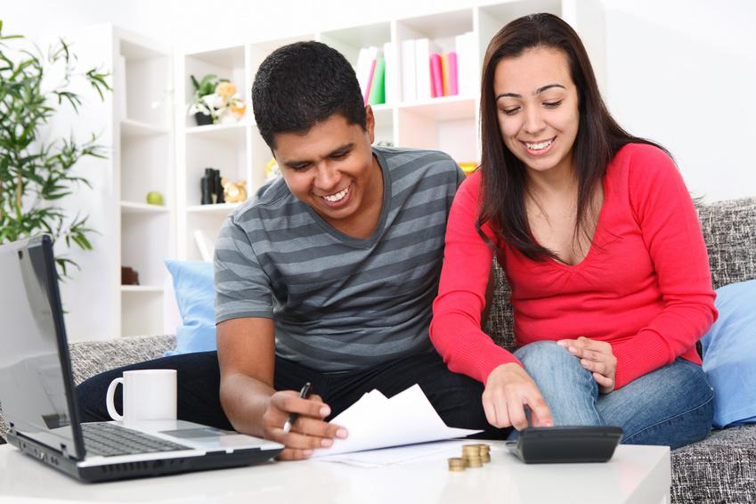 Young Hispanic/Latinx couple looking at financial papers and using a calculator