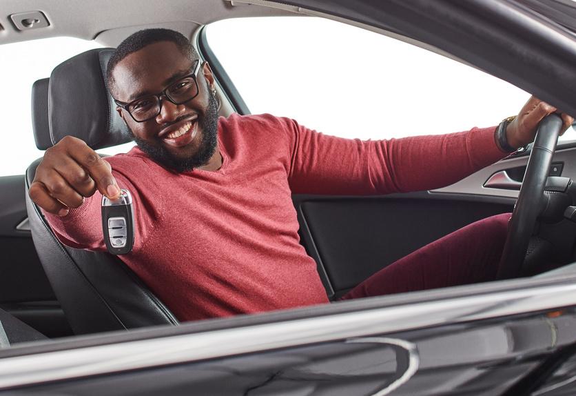 Man sitting in driver's seat of car and showing car keys