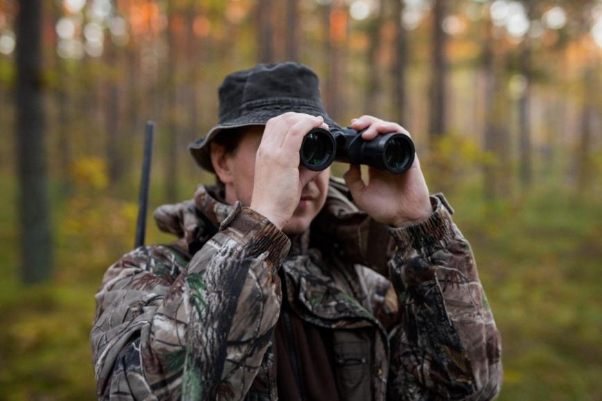 Man holding binoculars in the woods